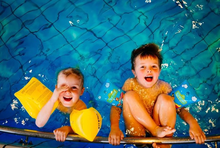 2 young children swimming to improve gross motor skills